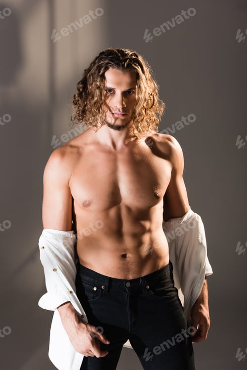 Preview: sexy man with taking off shirt on dark background