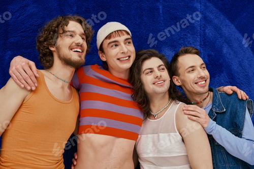 Preview: four jolly appealing stylish gay friends in everyday bright attires on blue backdrop, pride month