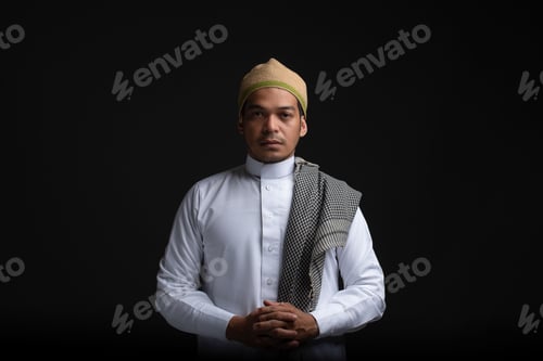 Preview: A Muslim male in a traditional headdress and outfit posing on a black background