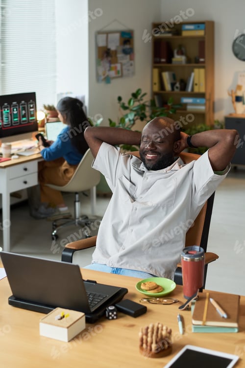 Preview: Black Man Relaxing at Desk in Modern Office Workspace