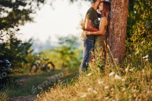 Preview: Leaning on the tree. Beautiful young couple have a good time in the forest at daytime