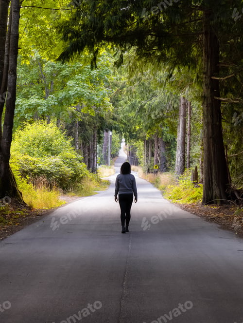 Preview: Adventurous Caucasian Woman walking on a Scenic Road