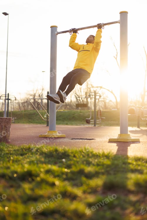 Preview: Man doing pull ups while working out in an outdoor gym