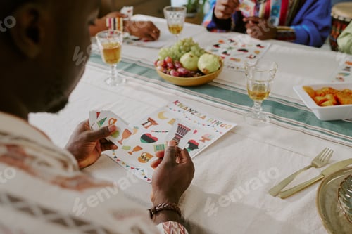 Preview: Young Black Man Playing Kwanzaa Bingo with Friends during Holiday Gathering