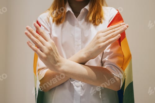 Preview: teenage girl generation Z with her arms crossed at her chest and lgbt pride flag demonstrates Break