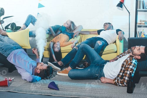 Preview: man smoking electronic cigarette while drunk friends sleeping after party
