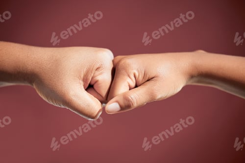 Preview: Cropped shot of two unrecognizable people fist bumping in studio against a red background
