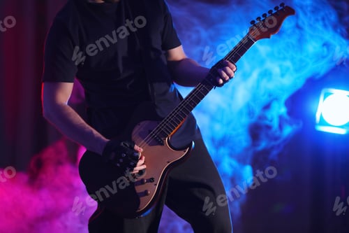 Preview: Man playing electric guitar on stage, closeup. Rock music