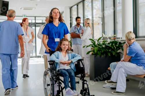 Preview: Young nurse pushing little girl on wheelchair at hospital corridor.
