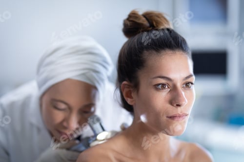 Preview: Female doctor checking patient with dermatoscopy in clinic