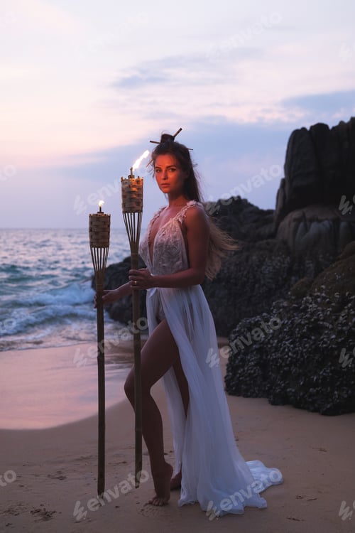 Preview: Beautiful bride with torches on the beach during beach wedding ceremony