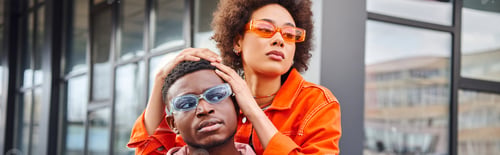 Preview: Confident and trendy young african american woman in sunglasses and bright outfit posing with best