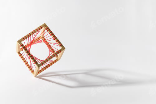 Preview: Platonic solid wooden cube with red thread on edge over white background