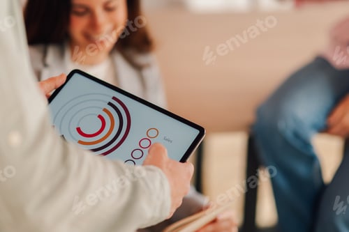 Preview: Businessman showing sales chart on tablet to colleagues during meeting