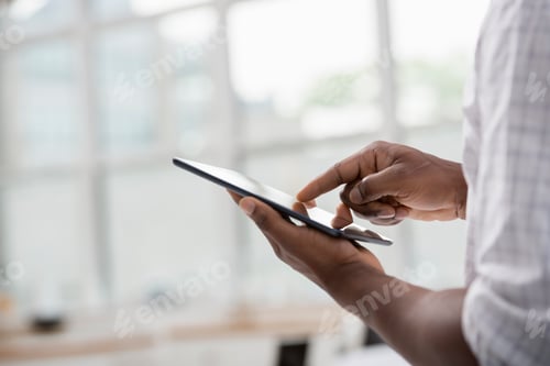 Preview: Professionals in the office. A man in a white shirt using a digital tablet.
