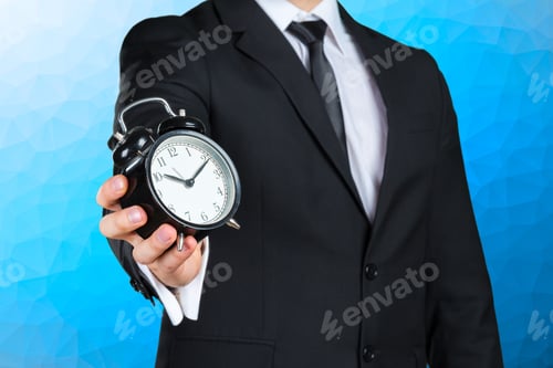 Preview: Unrecognizable businessman with an alarm clock in a hand
