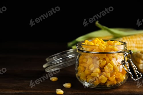 Preview: Tasty sweet corn kernels in jar on wooden table. Space for text