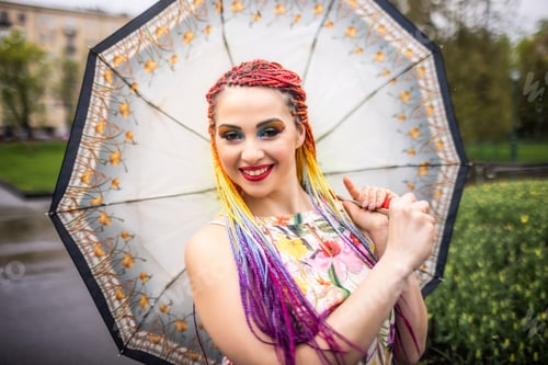 Preview: A pretty girl in a beautiful dress with bright multi-colored braids and shiny makeup is whirling in