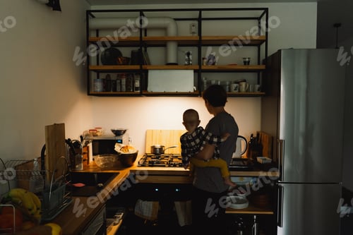 Preview: A mother holds her daughter in her arms in the kitchen.