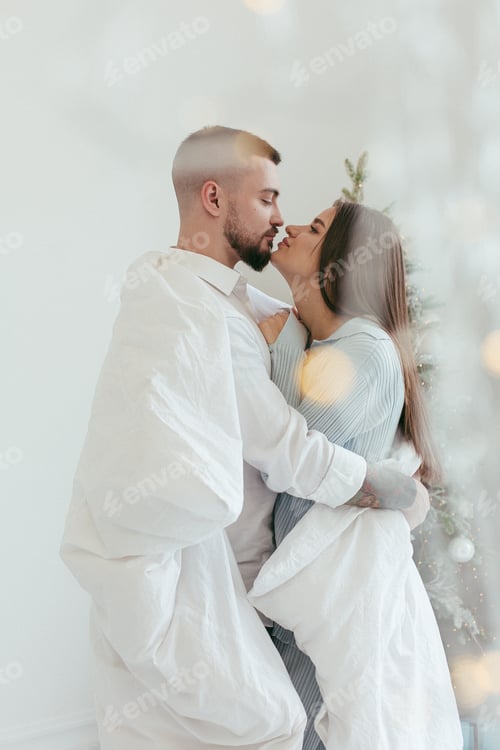 Preview: Couple in love under blanket near the christmas tree