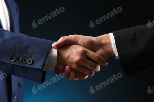 Preview: Business partners shaking hands on dark blue background, closeup