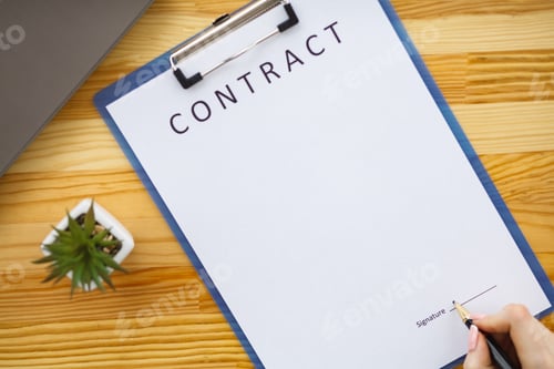 Preview: Business woman sitting at office desk signing a contract with shallow focus on signature.