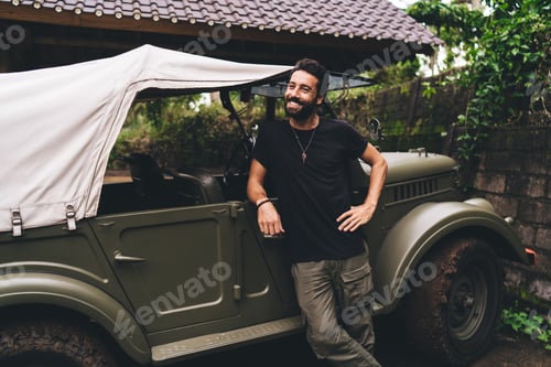 Preview: Cheerful businessman relaxing near automobile in Bali