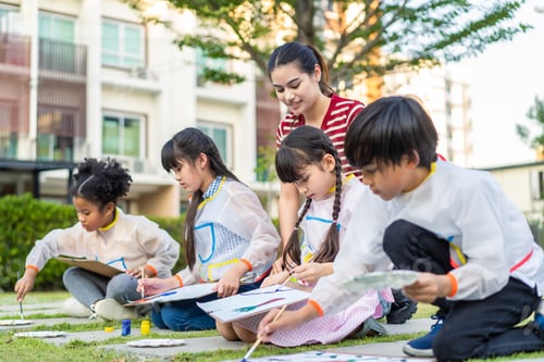 Preview: Group of student coloring on painting board outdoors in school garden.