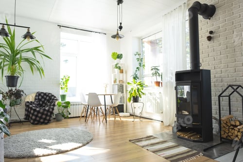 Preview: The interior of the house with large windows and home plants round table, metal stove fireplace, cha