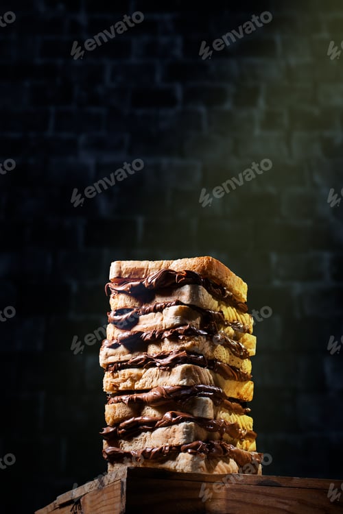 Preview: Large chocolate cream sandwich consisting of several pieces of toasted bread against a brick wall