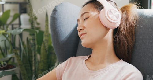 Preview: Woman with casual wear headphone close eyes use phone listen calm music relax in living room.