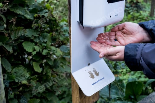 Preview: Close up of person using automatic hand sanitizer dispenser during Corona virus crisis.