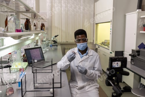 Preview: Young scientist in protective mask, gloves and labcoat testing new vaccine