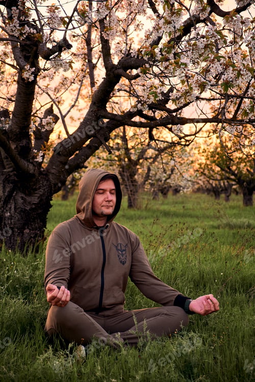 Preview: Man meditating in a park at sunset. Healthy lifestyle