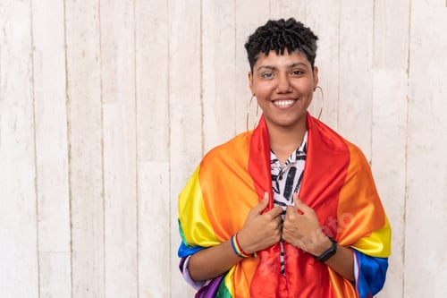 Preview: Happy lesbian woman with arms outstretched holding rainbow flag