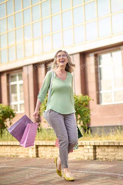 Preview: Woman with bags walking down street after shopping