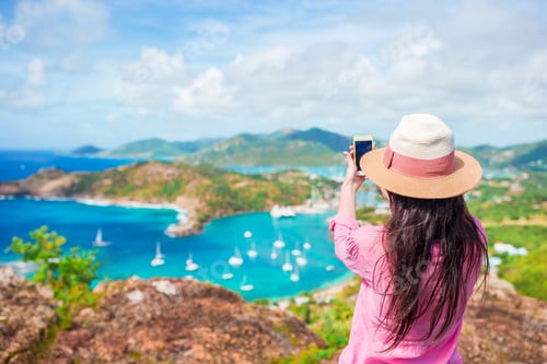 Preview: Young tourist woman making photo of English Harbor from Shirley Heights, Antigua, paradise bay at