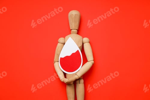 Preview: Wooden mannequin with a red drop on a red backdrop