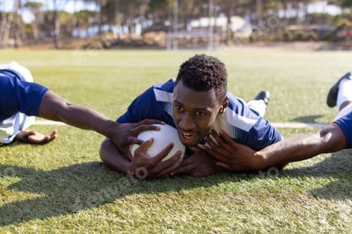 Preview: Three African American young male athletes train with rugby ball on a grass field