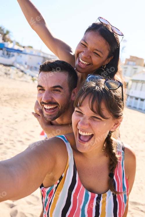 Preview: Group of cheerful diverse young gen z friends taking a selfie on the beach