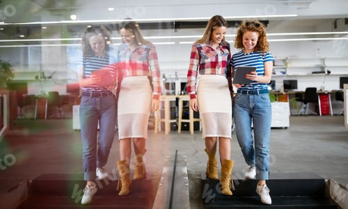 Preview: Colleagues discussing business and smiling while walking through the office corridor