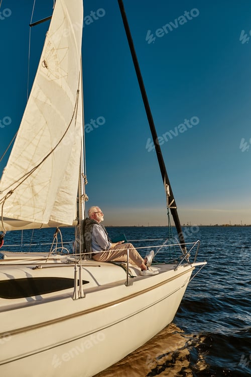 Preview: Vertical shot of carefree retired man enjoying amazing view and relaxing while sitting on the