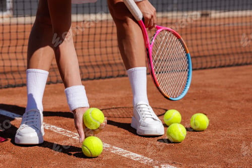 Preview: Female player collecting balls on clay court during practice