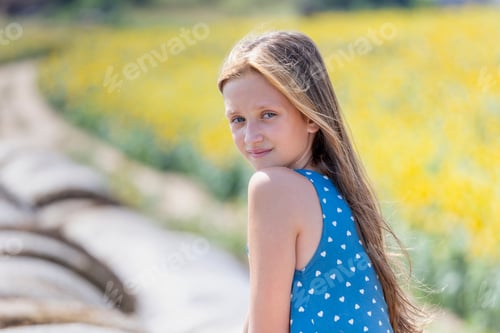Visualização: Retrato de menina bonita com cabelos longos em cima do fardo de feno redondo sorrindo para a câmera no verão