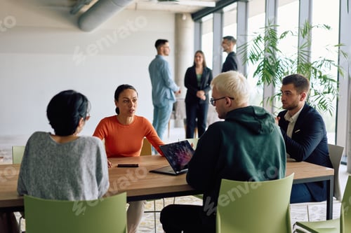Preview: A diverse team of business professionals engaged in a discussion around a conference table in an