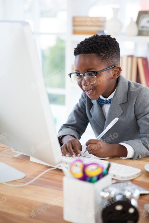 Preview: Smiling businessman writing report while looking at computer