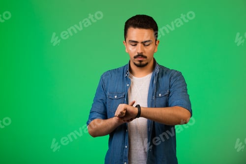 Preview: Man looking to his watch, checking time in a quite manner