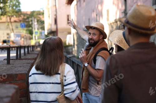 Preview: Guide with microphone and tourists on city street during excursion