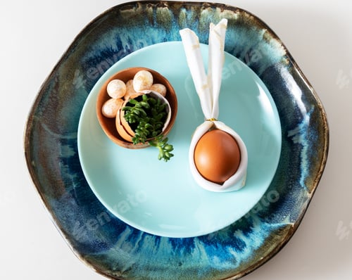 Preview: Top view flat lay egg with bunny ears on blue plate serving for easter celebration.