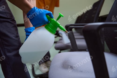 Preview: Professional cleaning company worker spray-disinfecting chairs with chemicals